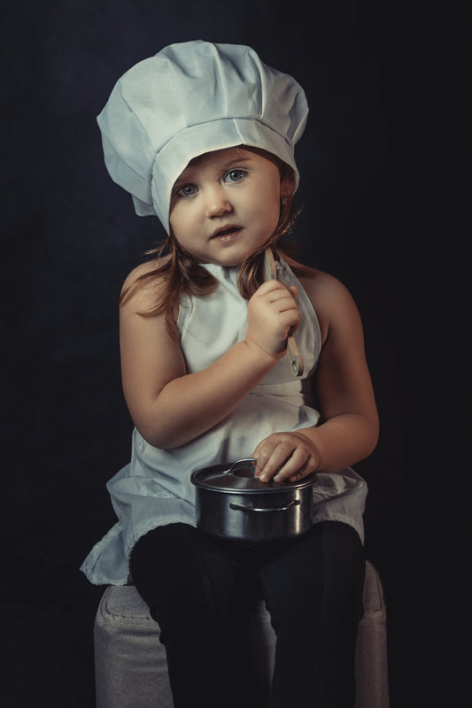 a little girl wearing a chef's hat and holding a pot