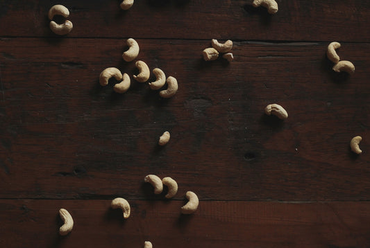 Cashews are scattered on a dark wooden surface.