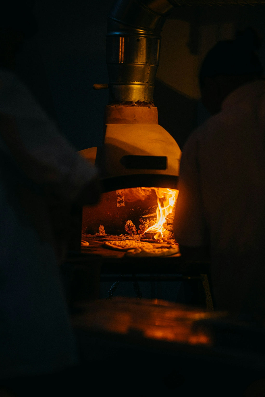 Wood-fired oven with glowing embers and burning embers inside.
